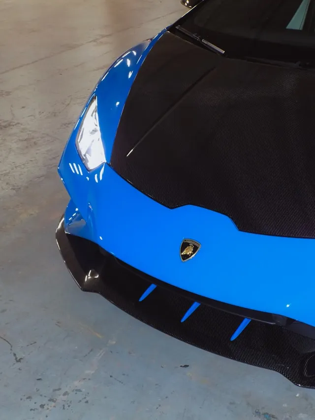 Glossy blue supercar with a carbon fiber hood, overhead view