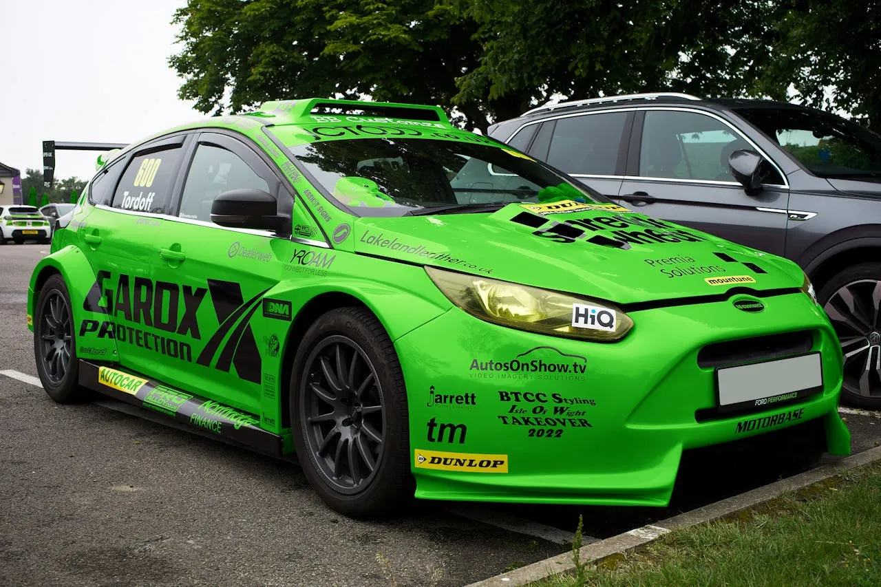 Lime green hatchback touring car covered in sponsor decals and printed vinyl graphics
